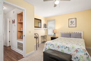 Un dormitorio con cama, escritorio, silla, armario y ventilador de techo.