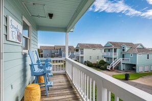 Un bâtiment situé sur la côte, doté d’une terrasse en bois, de chaises bleues et d’une enseigne indiquant « Sandy T’s ».
