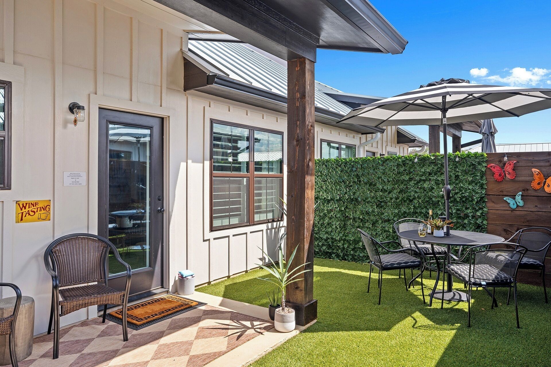 A patio with outdoor seating, a hedge, and a sign indicating wine tasting.