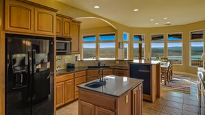 Una cocina amplia con armarios de madera, un refrigerador negro y una isla grande con un fregadero.