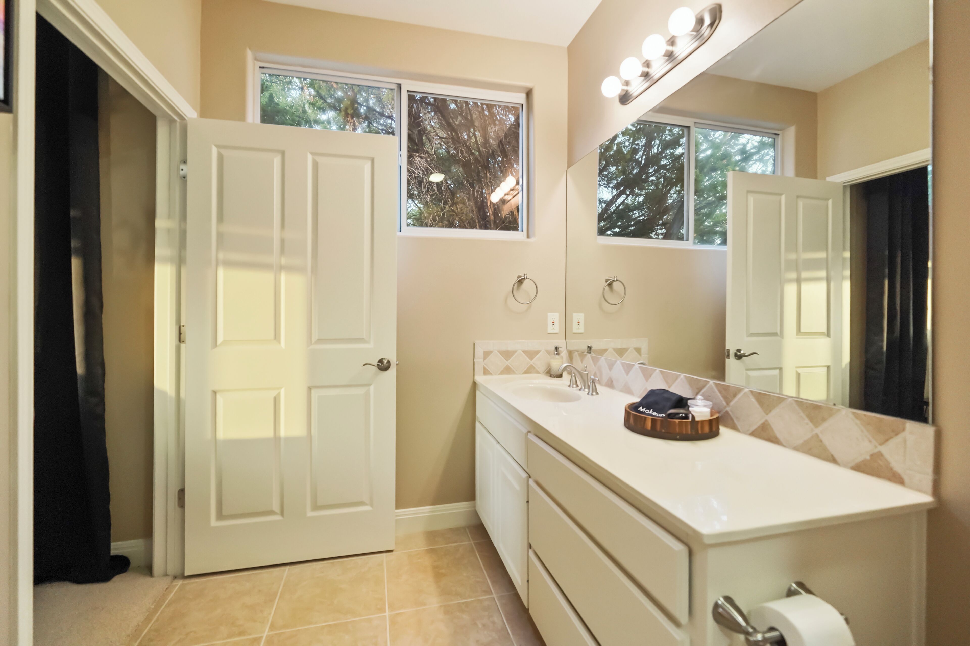 A bathroom with a white vanity, a mirror, and a window.