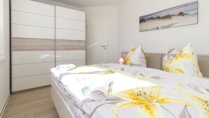 A bedroom with a bed, a wardrobe, a painting, and a nightstand.