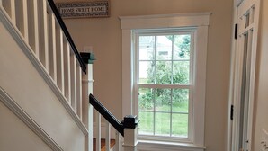 A staircase with white railings and a wooden handrail, leading to a landing with a window.