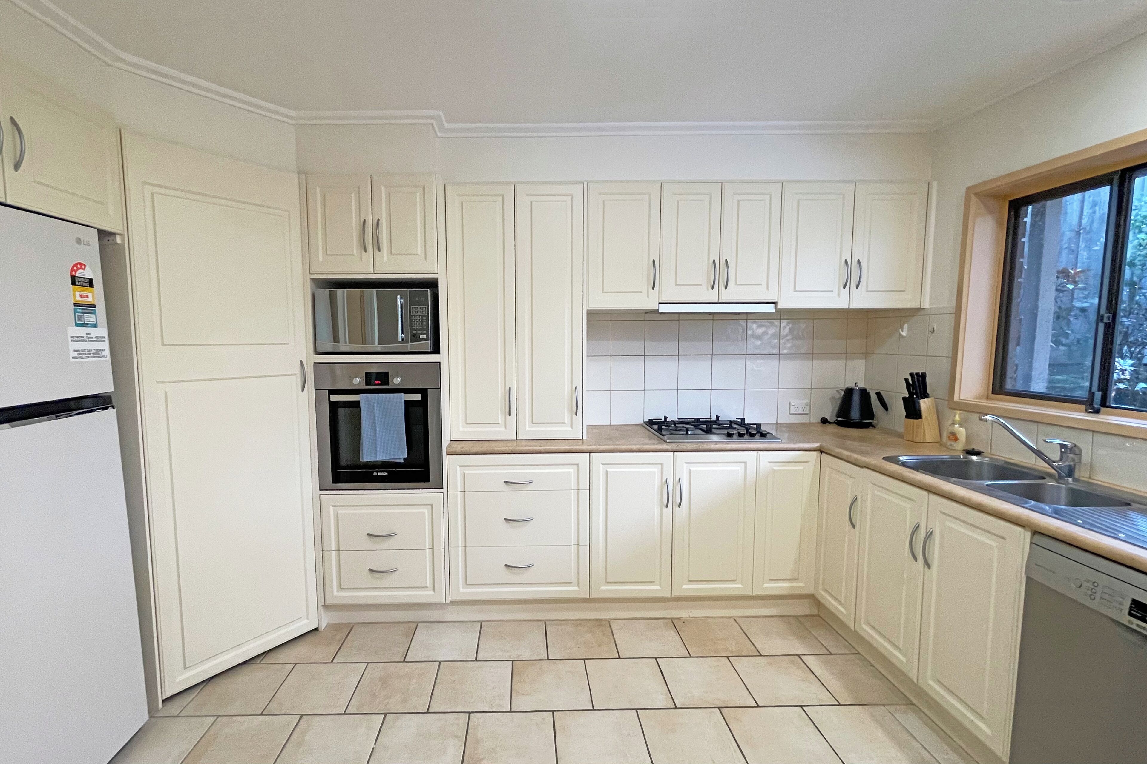 A kitchen with white cabinets, a stainless steel refrigerator, an oven, a microwave, a gas stove, and a dishwasher.