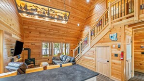 L’intérieur d’un chalet en bois, avec une cheminée, un canapé, une table à manger et un escalier.