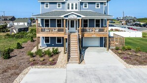 Ein zweistöckiges Haus mit Veranda, Garage und einer Terrasse.