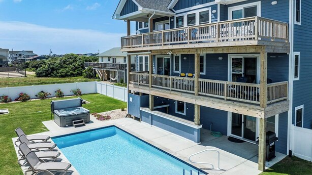 Ein zweistöckiges Haus mit großzügigem Balkon, Schwimmbad und Whirlpool.
