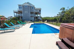 A swimming pool with lounge chairs and a hot tub, surrounded by a fence and a building with balconies. - Oceanside, Private Pool, Hot Tub, Close to Beach, WW874, Whalecome Aboard (Corolla)