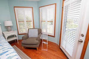A room with a patterned armchair, a small side table with a lamp, and a clear storage unit. - Oceanside, Private Pool, Hot Tub, Close to Beach, WW874, Whalecome Aboard (Corolla)