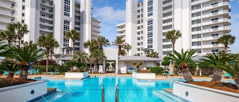 A modern hotel with a central pool surrounded by palm trees and lounge chairs.