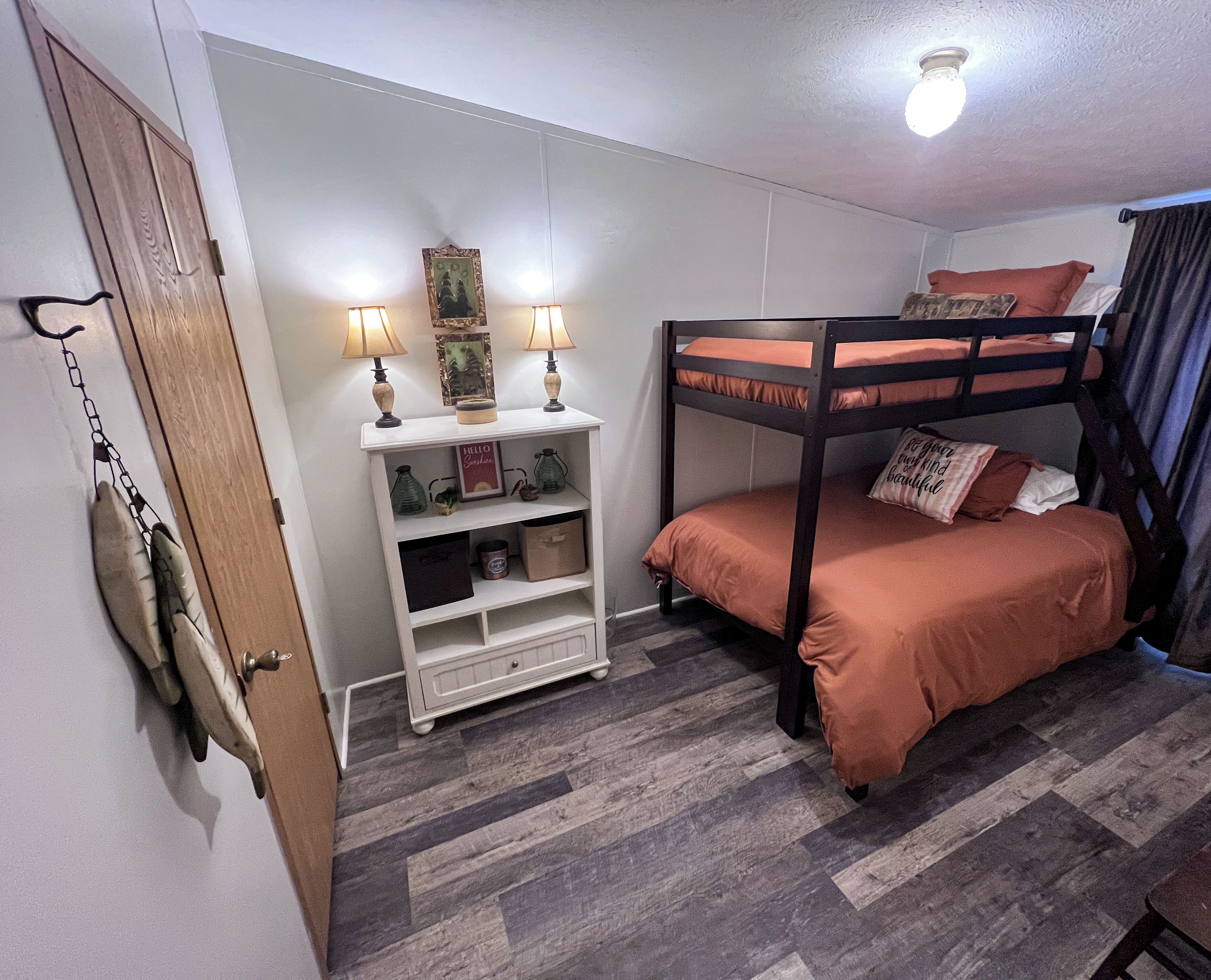 Ein Etagenbett mit Kopfteil, ein weißes Regal mit Dekoration und eine Tür mit Schlüsselloch.