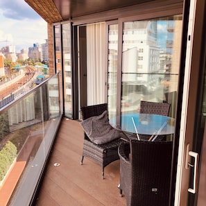 Enjoy the city view from this balcony with a glass table and two chairs.