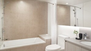 Een moderne badkamer met een bad, toilet en wastafel.