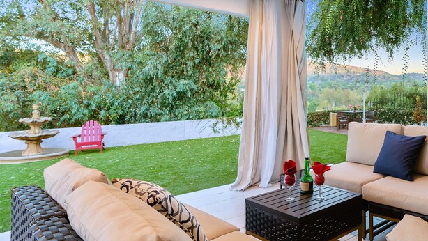 An outdoor patio with a sofa, a table, and a chair. - 5-Min Walk To Rose Bowl - Luxe Estate! (Pasadena)
