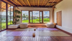 Une salle de yoga dotée de planchers en bois, de grandes fenêtres et de deux fauteuils en forme de poire.