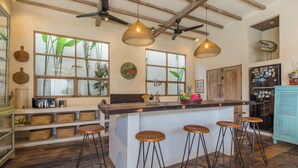 Une cuisine avec des tabourets de bar en bois, un îlot central et des luminaires suspendus.
