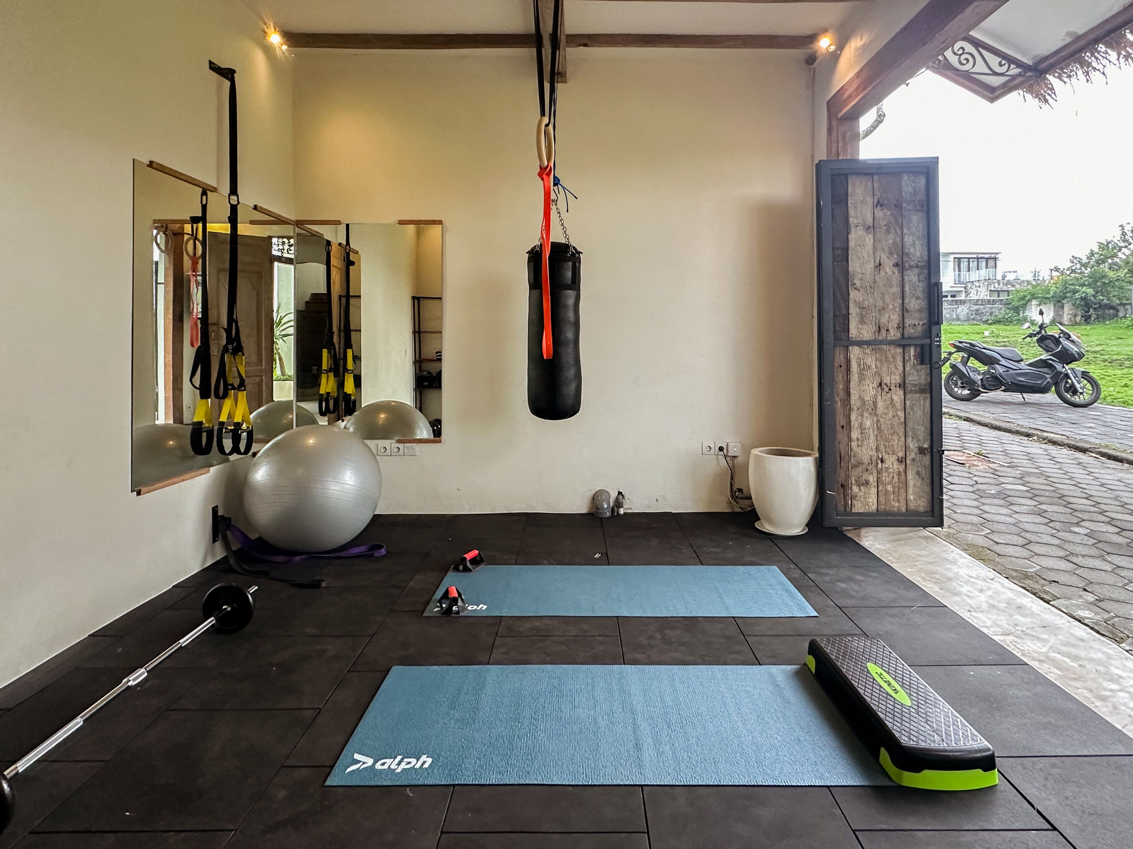 Een sportschool met trainingsapparatuur, matten en een bokszak.