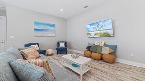Ein modernes Wohnzimmer mit einem grauen Sofa, einem blauen Sessel, einem weißen Couchtisch und zwei an der Wand befestigten Bildern.