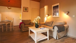 A cozy living room with a wooden ceiling, a dining area with a table and chairs, and a sofa with a vase of flowers. - Lovely apartment for 6 guests with WIFI, pool, TV, terrace and pets allowed (Parentis-en-born)