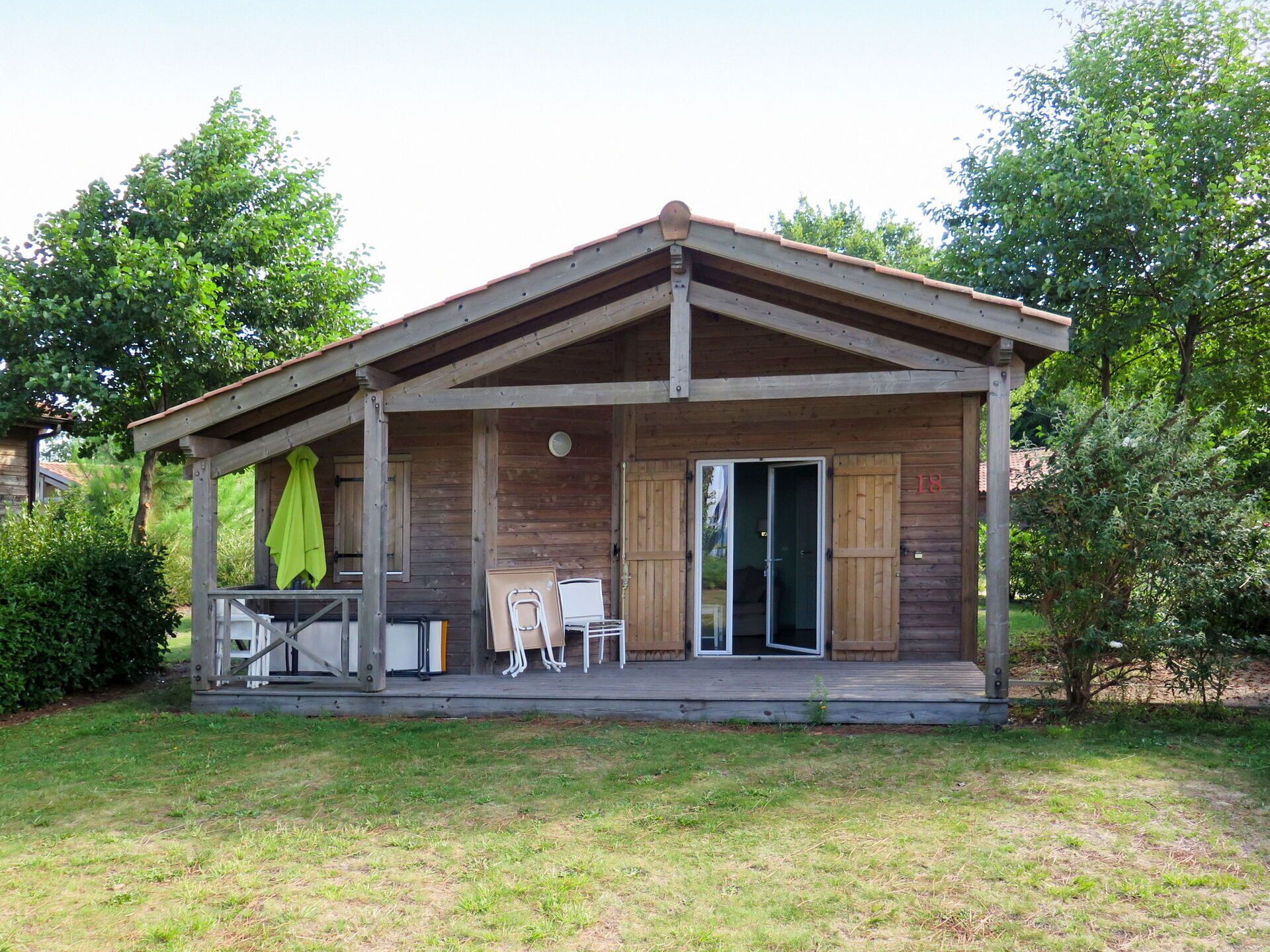 A wooden cabin with a covered porch, a sliding glass door, and a small patio area with outdoor furniture.