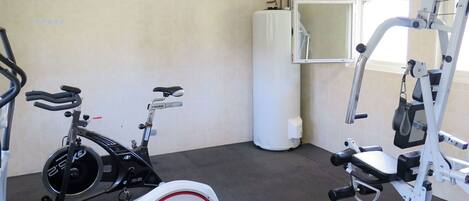 A gym with a stationary bike, an elliptical, and a weight machine.