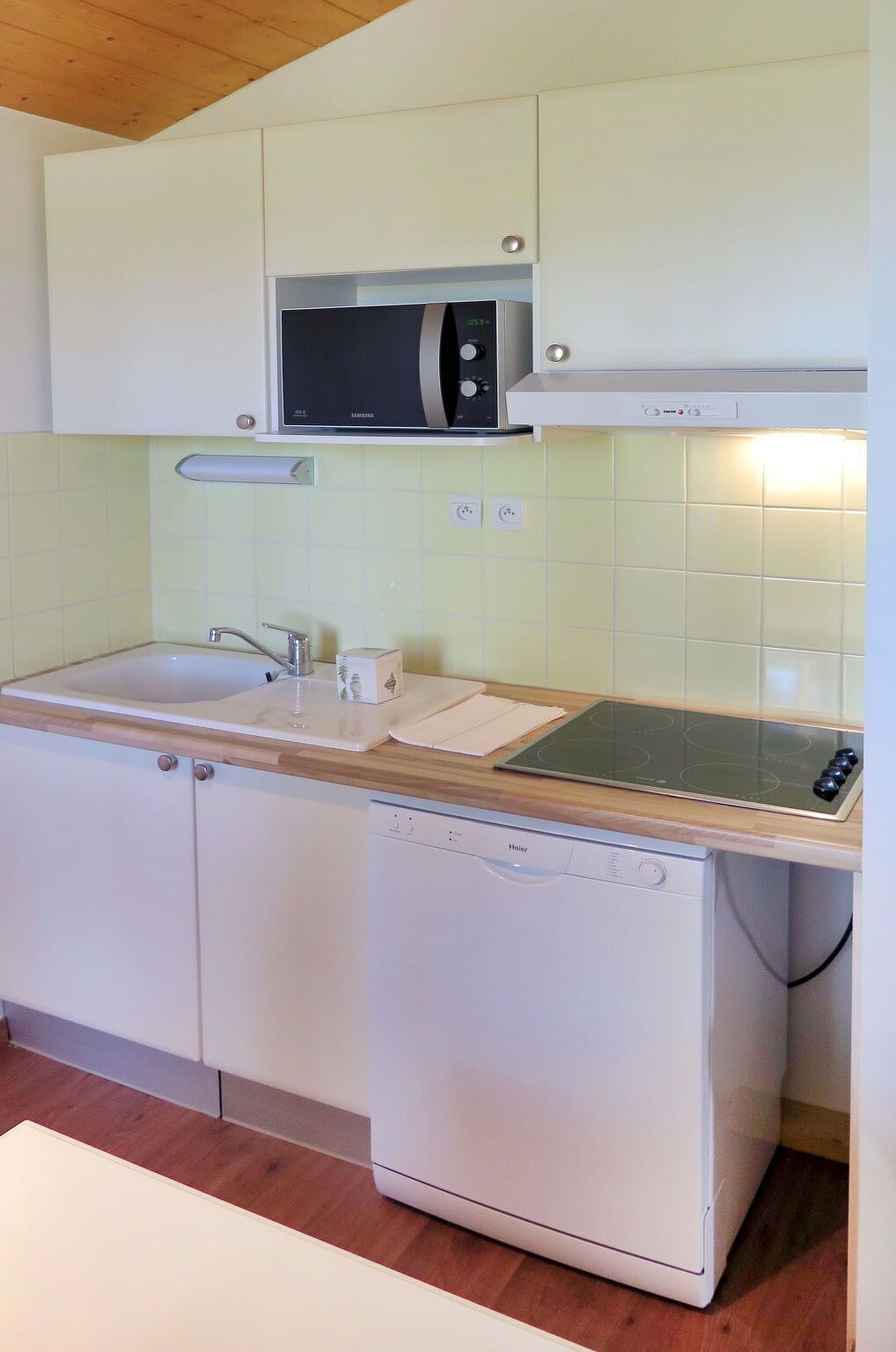 A compact kitchen with a microwave, stove, and dishwasher.