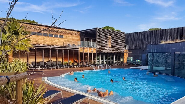 Une piscine dotée de chaises longues et un bâtiment à l’architecture moderne.