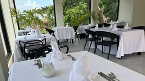 A restaurant with tables set for dining, featuring white tablecloths and neatly arranged cutlery. - High Life Resort & Spa (Negril)