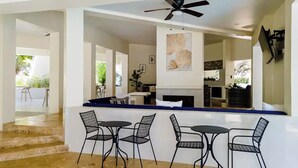 A modern outdoor dining area with a stone floor, black metal chairs, and a ceiling fan. - High Life Resort & Spa (Negril)