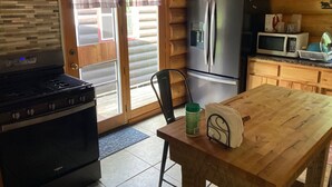 A kitchen with a stove, refrigerator, microwave, and a wooden table. - Custom built log home on 40 acres & in the woods!
Snowmobile right from home! (Barnum)