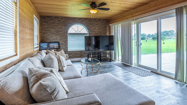 Ein modernes Wohnzimmer mit Ecksofa, Fernseher und Deckenventilator.