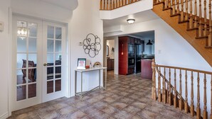 Ein geräumiger Eingangsbereich mit einer Holztreppe, einem weißen Konsolentisch und einem Kronleuchter.