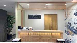 A reception desk with a sign for Y&Y Namba Hotel Osaka, a plant, and a traditional Japanese screen. - Y&Y NAMBA HOTEL Osaka (Osaka)