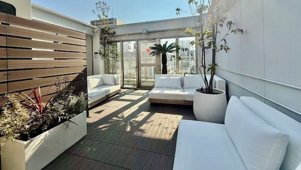 A rooftop terrace with a wooden slatted wall, a white sofa, and potted plants. - Y&Y NAMBA HOTEL Osaka (Osaka)