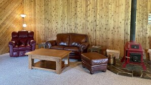 Ein gemütliches Zimmer mit Holzboden, einem Ledersofa, einem Holztisch und einem Kamin.