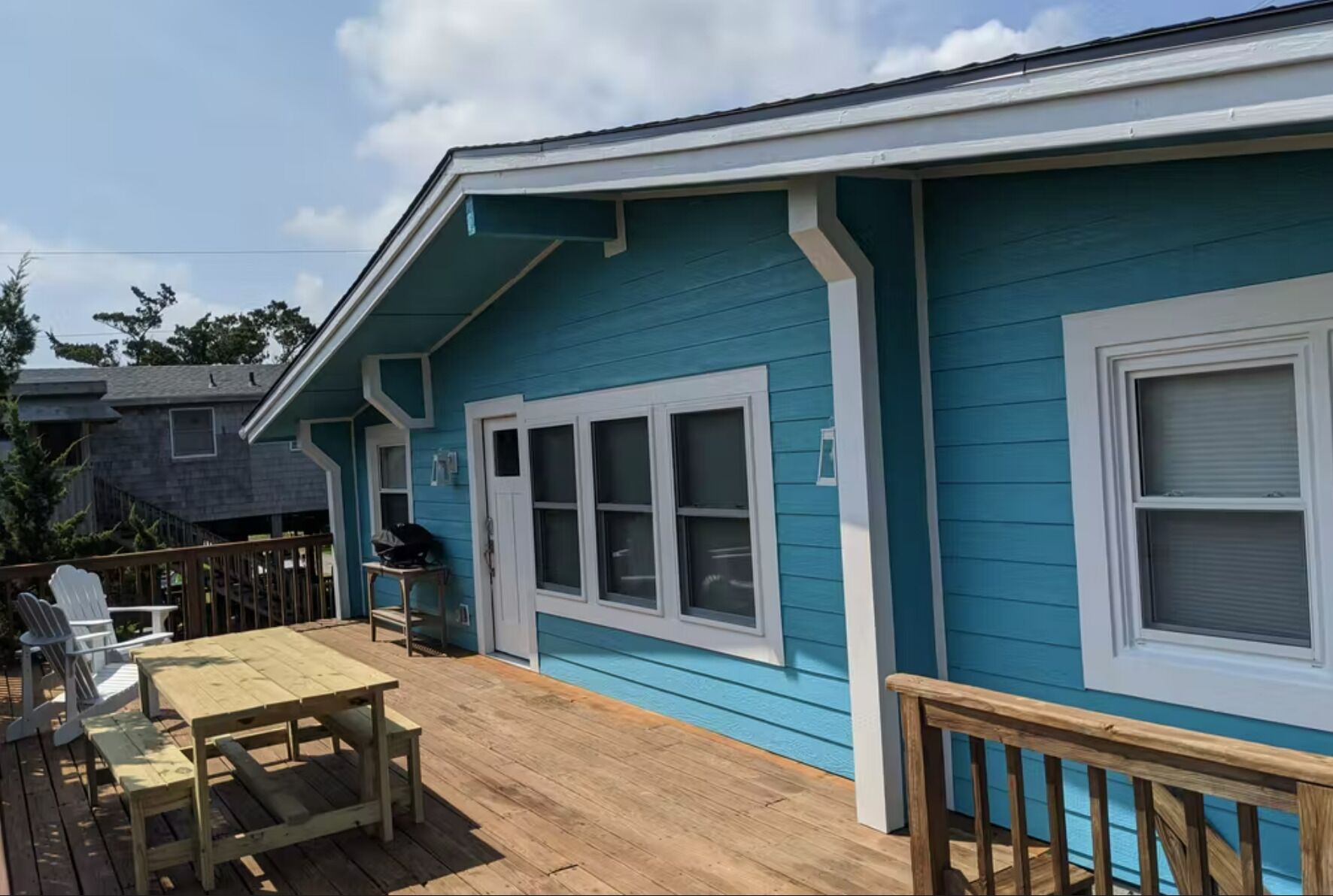 Een blauw huis met een terras, witte ramen en een kleine tafel.