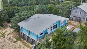 A two-story house with a blue exterior, a covered deck, and a fenced yard.