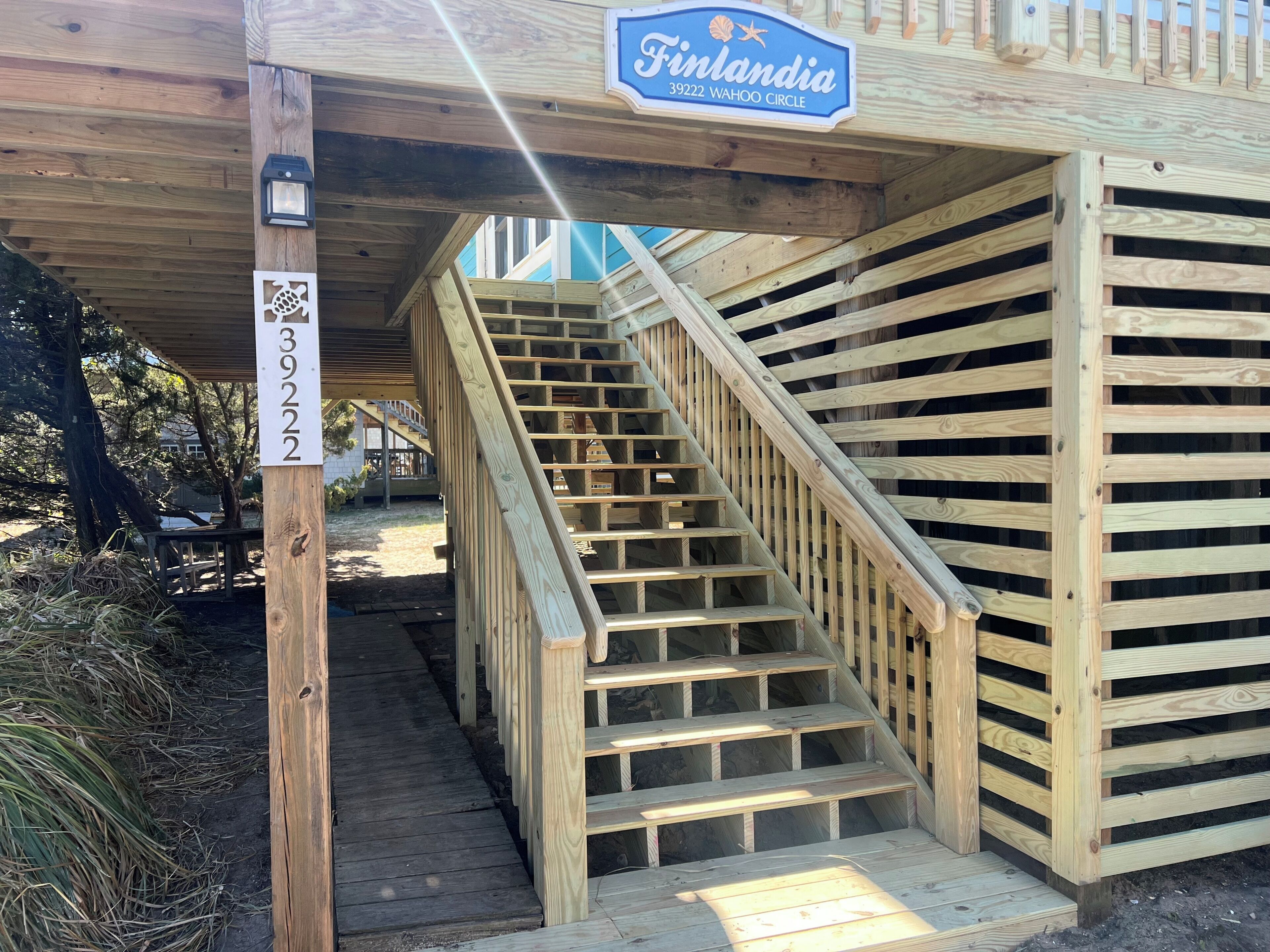 Un escalier en bois mène à une zone abritée où est affiché un panneau indiquant : « Finlandia 39222 WAHOO CIRCLE ».