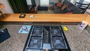 A kitchen with a gas stove, granite countertop, and a wooden bar.