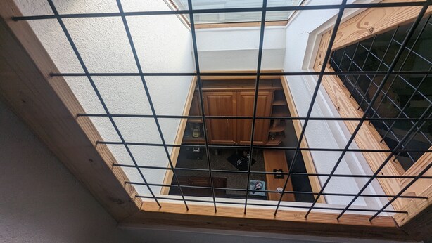 A view through a skylight with a grid pattern, revealing a kitchen area with wooden cabinets and a countertop.