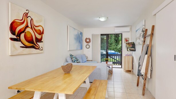 Una sala de estar con una mesa de madera, un sofá y un cuadro de frutas.