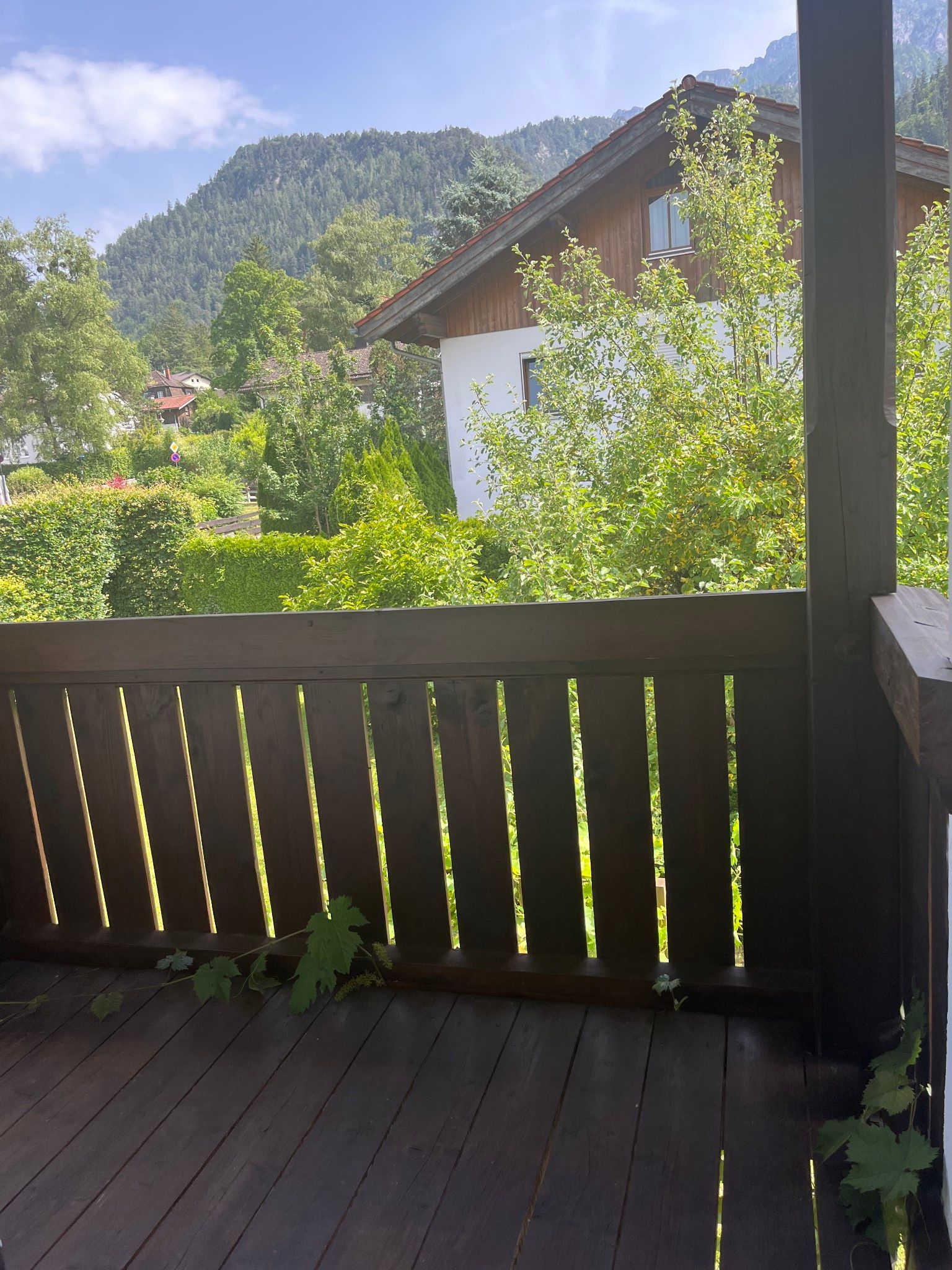 Een houten terras met uitzicht op een berg en een huis.