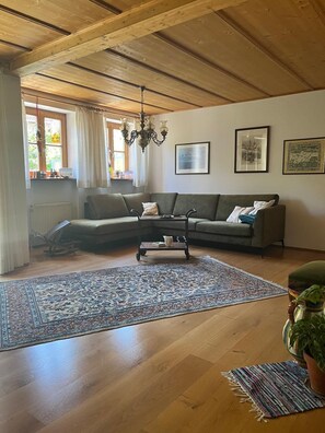 Un salon avec un plafond en bois, un canapé, une table basse et un grand tapis.