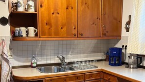 Een keuken met houten kastjes, een spoelbak en diverse keukenapparaten.