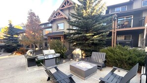 Un espacio al aire libre con un brasero, dos sillas Adirondack y una parrilla.