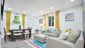 A modern living room with a dining area, a sofa, and a colorful striped rug.