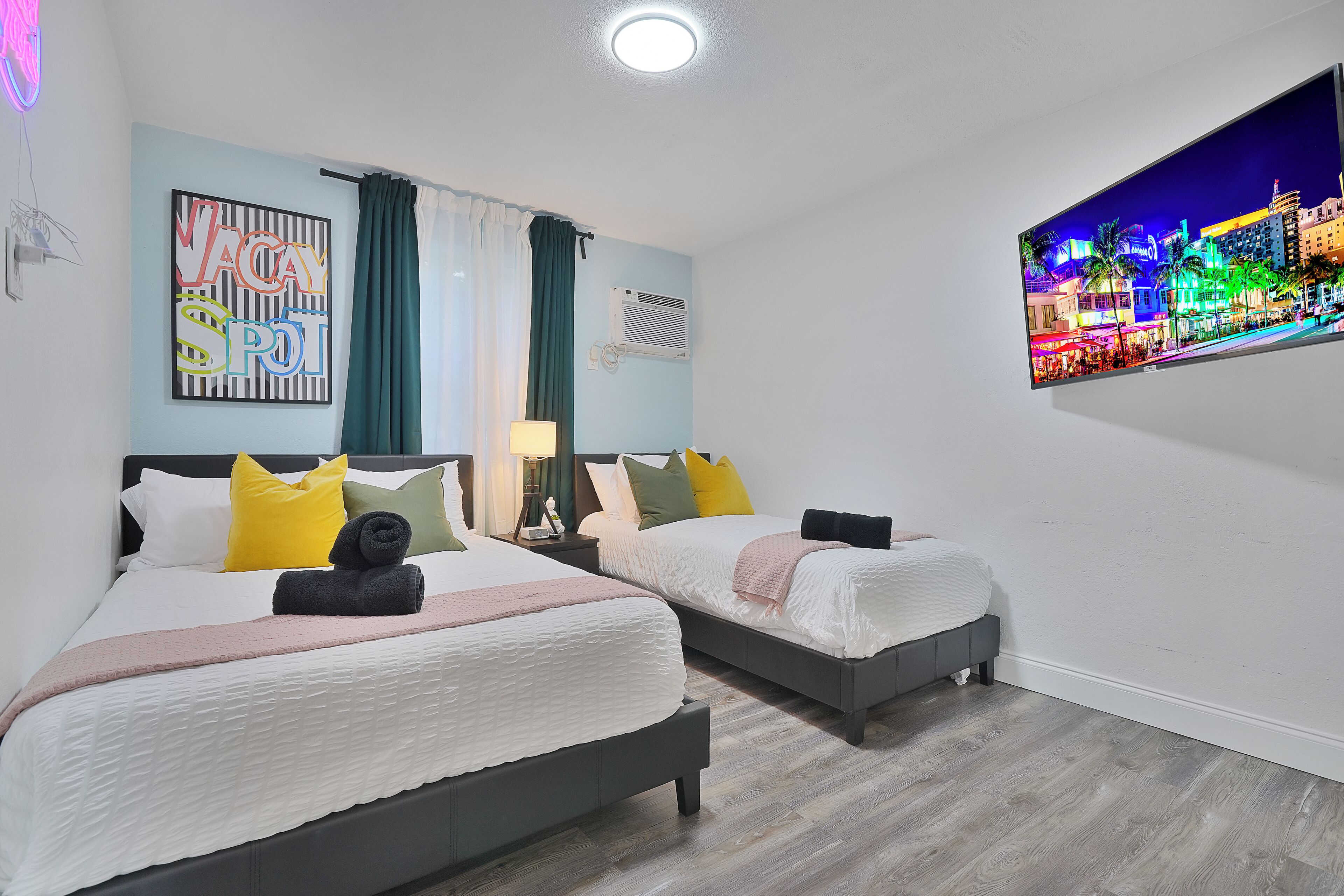Une chambre d’hôtel avec deux lits, un téléviseur à écran plat fixé au mur et une vue sur la ville.