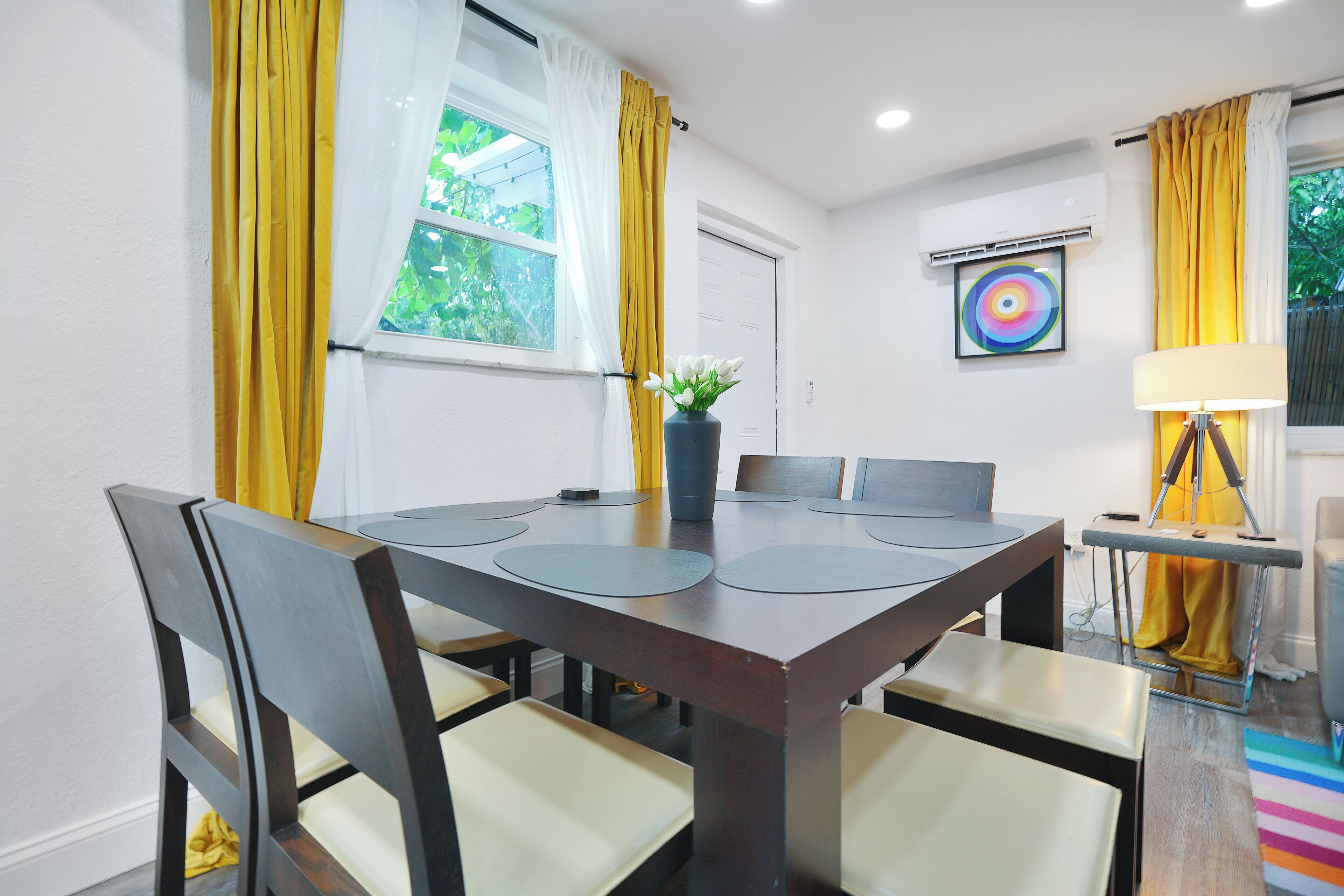 A dining area with a rectangular table, chairs, and a vase with flowers.