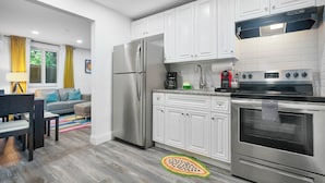 A modern kitchen with white cabinets, stainless steel appliances, and a colorful rug.