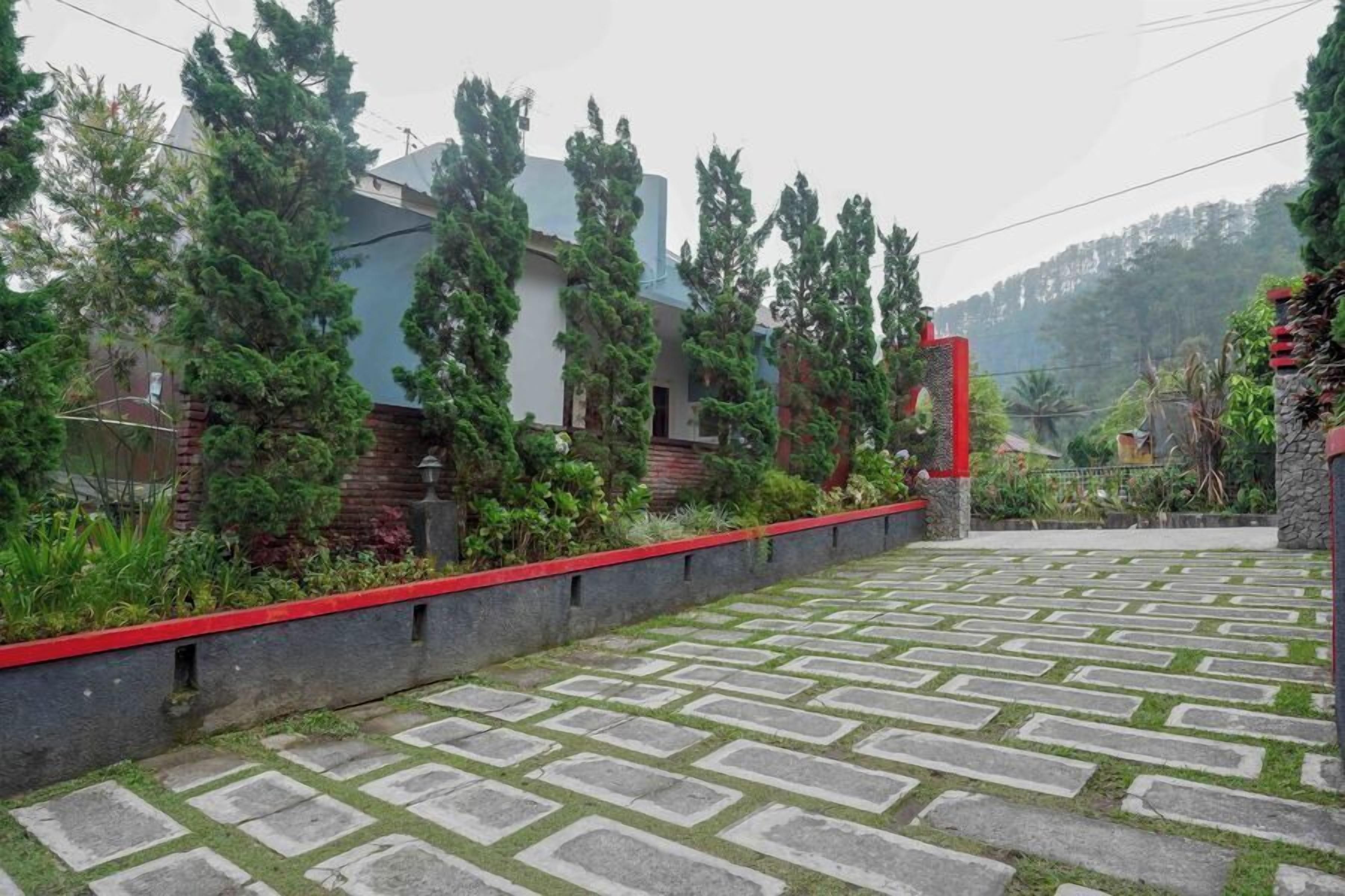 Un camino pavimentado con un diseño geométrico que conduce a un edificio con puerta roja.